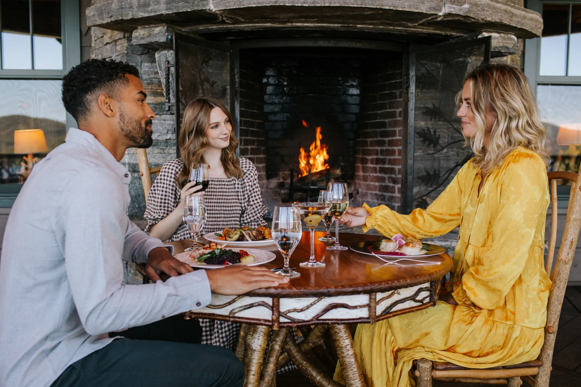 A man and woman have lunch with a woman in a yellow dress. 