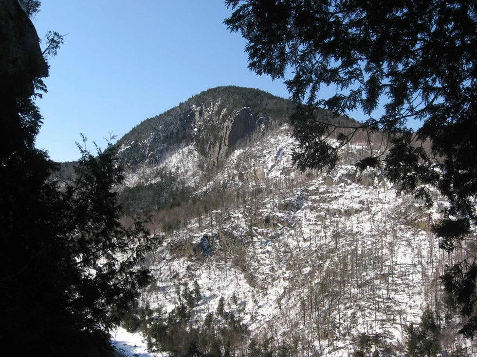 The view of a cliff from across a valley in the winter