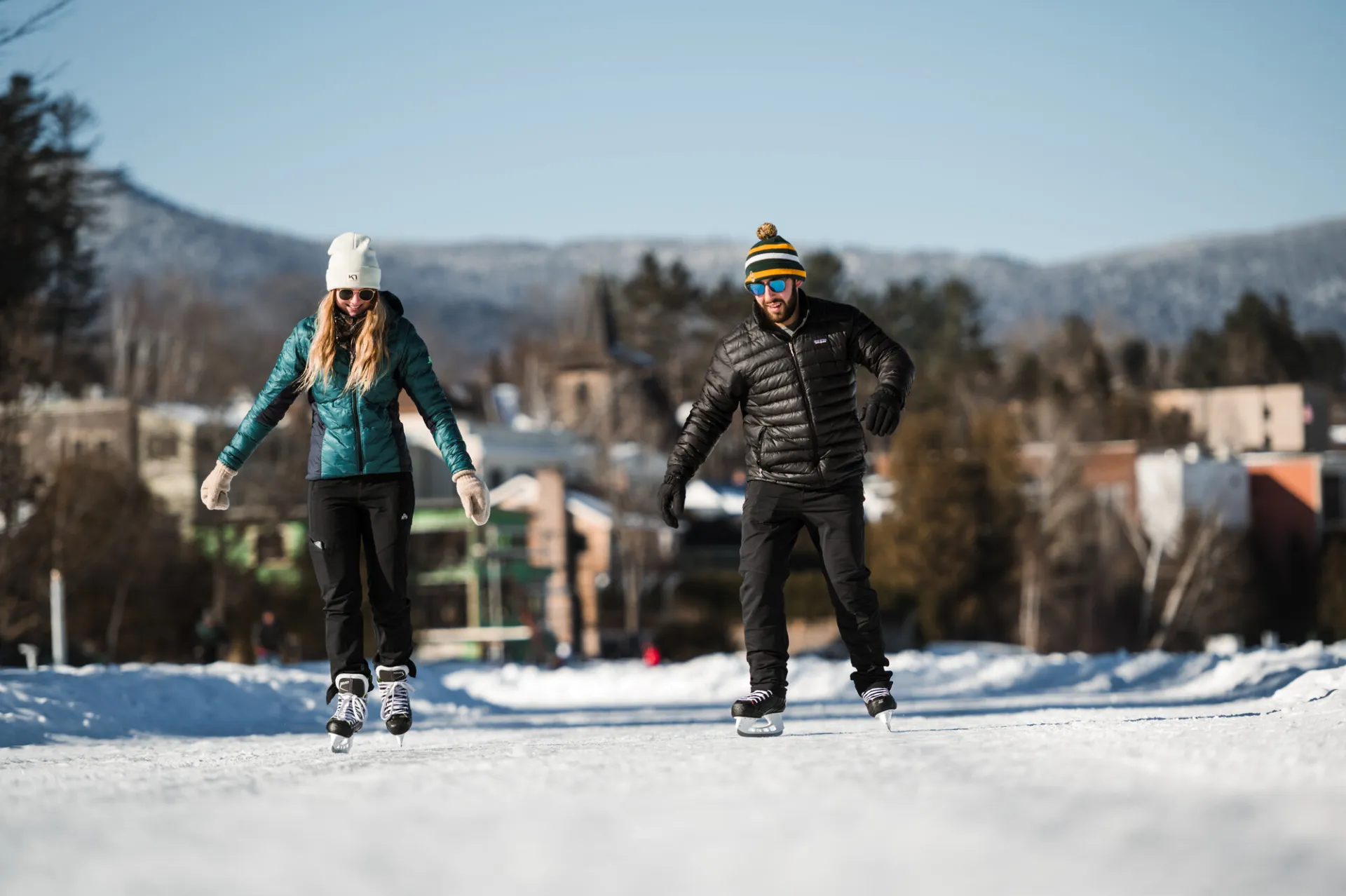 A man and woman skate on a frozen lake on a sunny winter day.