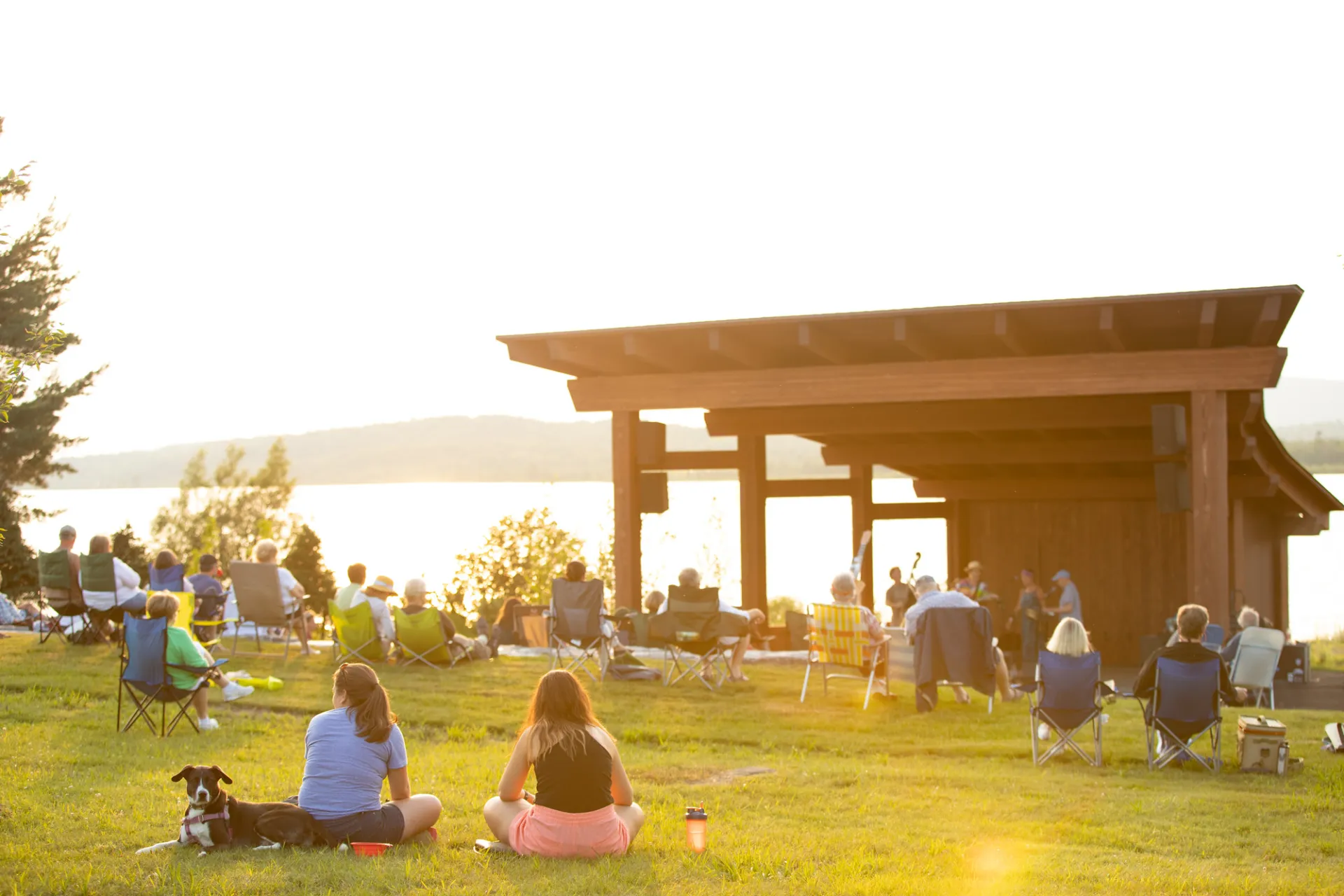 People sitting on a lawn listening to live music.