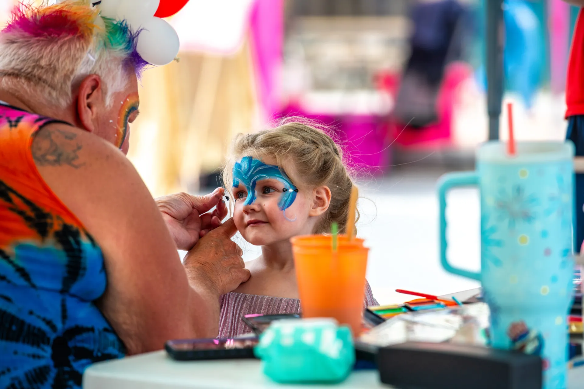 A young child gets their face painted.