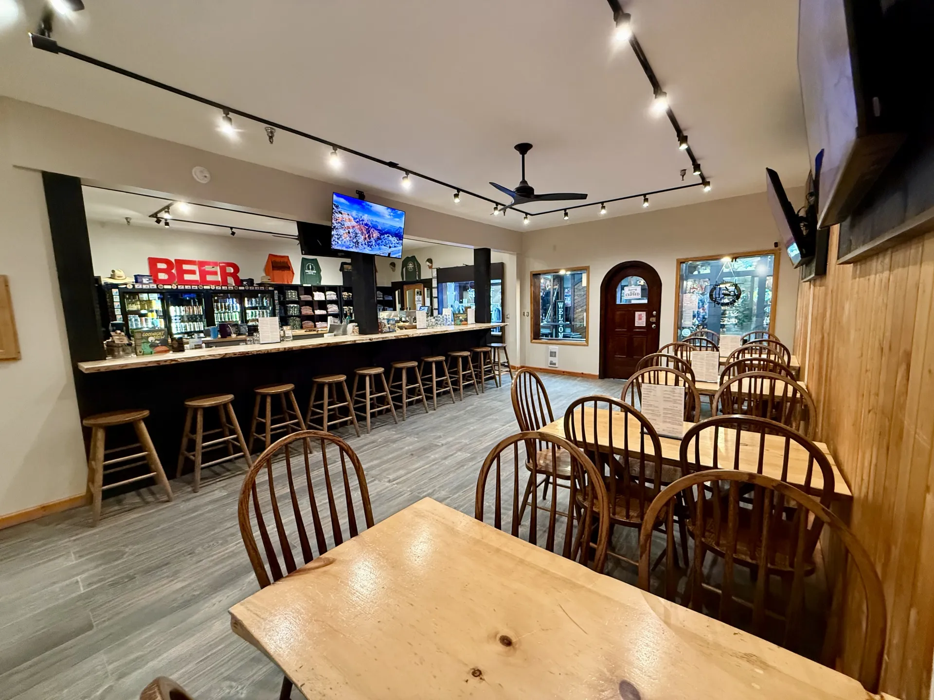 View from the far back corner of the dining space, bar area, coolers and swag shelves at Raquette River Brewing Taproom