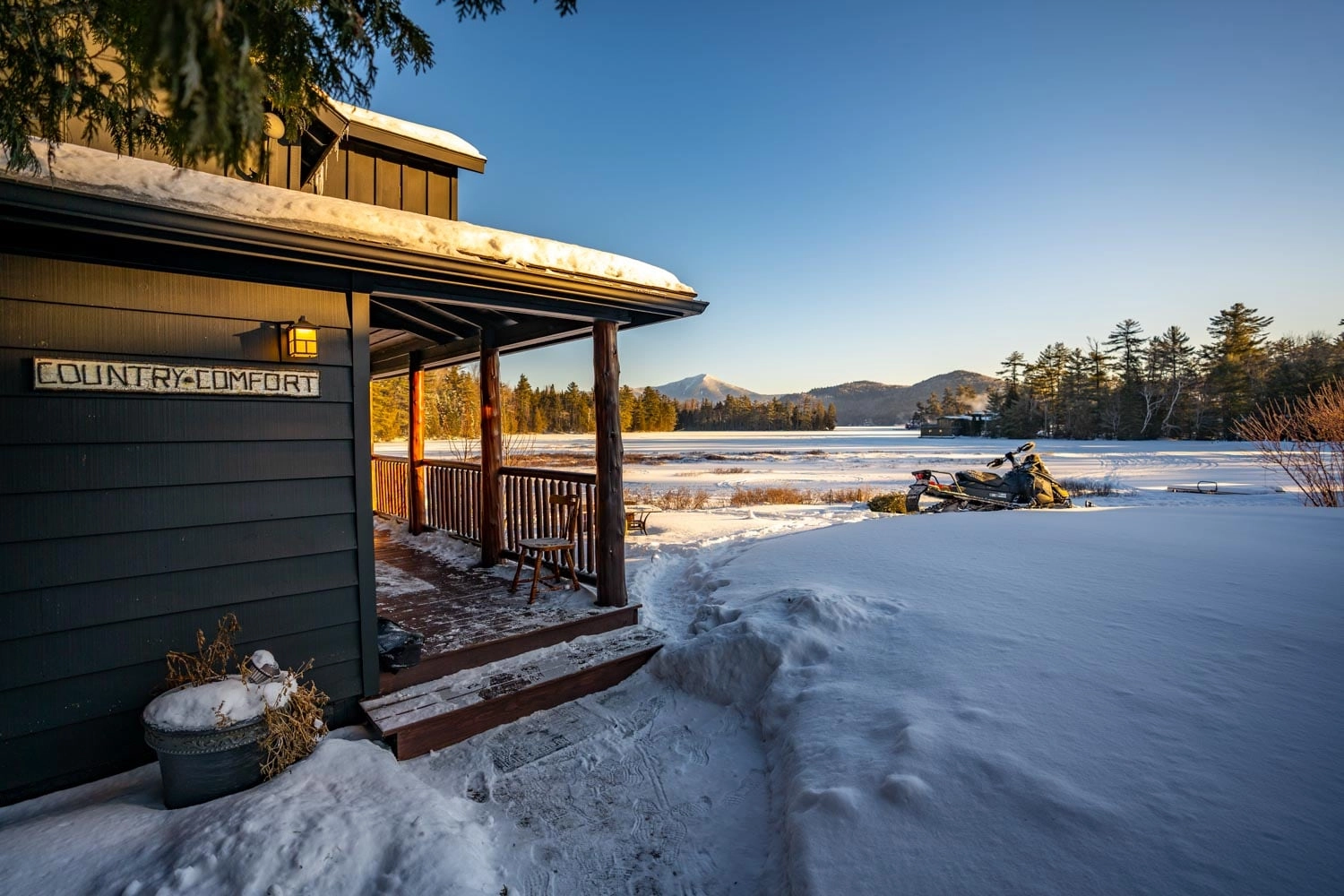 A snowmobile parked out side of a cabin in the snow.