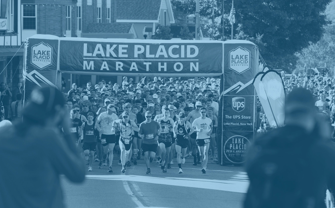 A group of runners start a marathon under a banner.