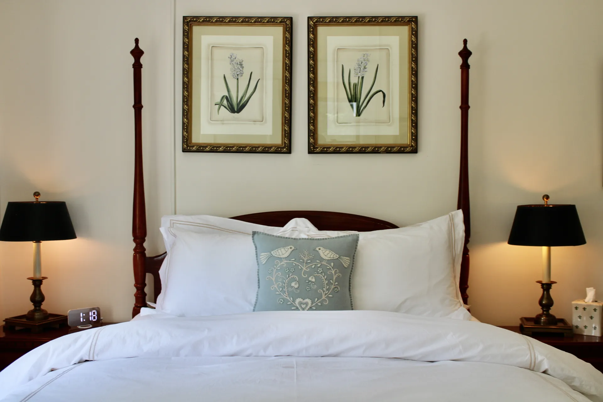 View from the foot of the bed looking at the dark four poster bed and wall art above.