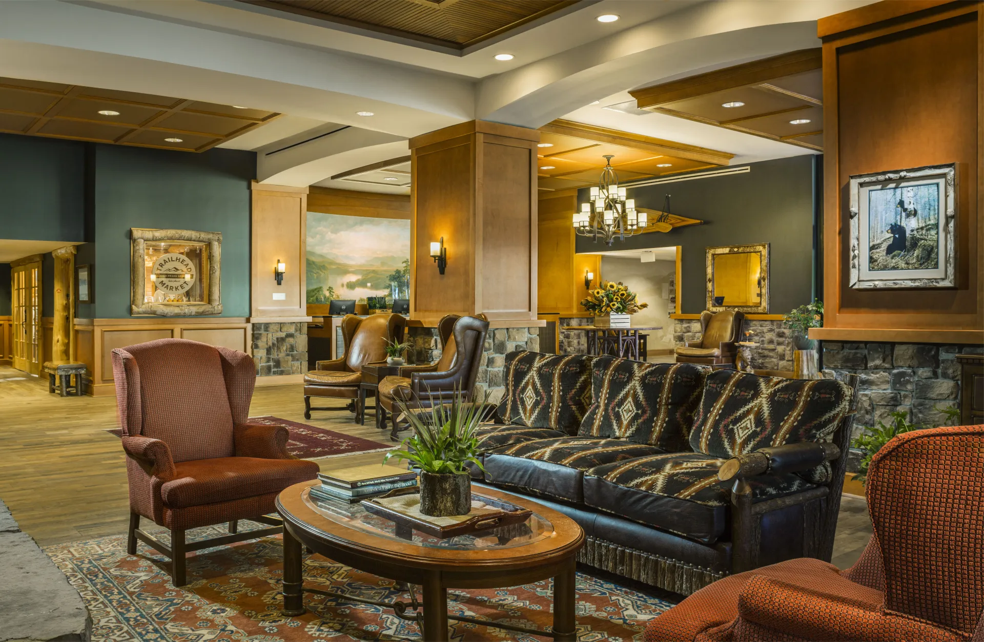 Sitting area in hotel lobby with patterned fabric and leather couch, wingback chairs, and coffee table
