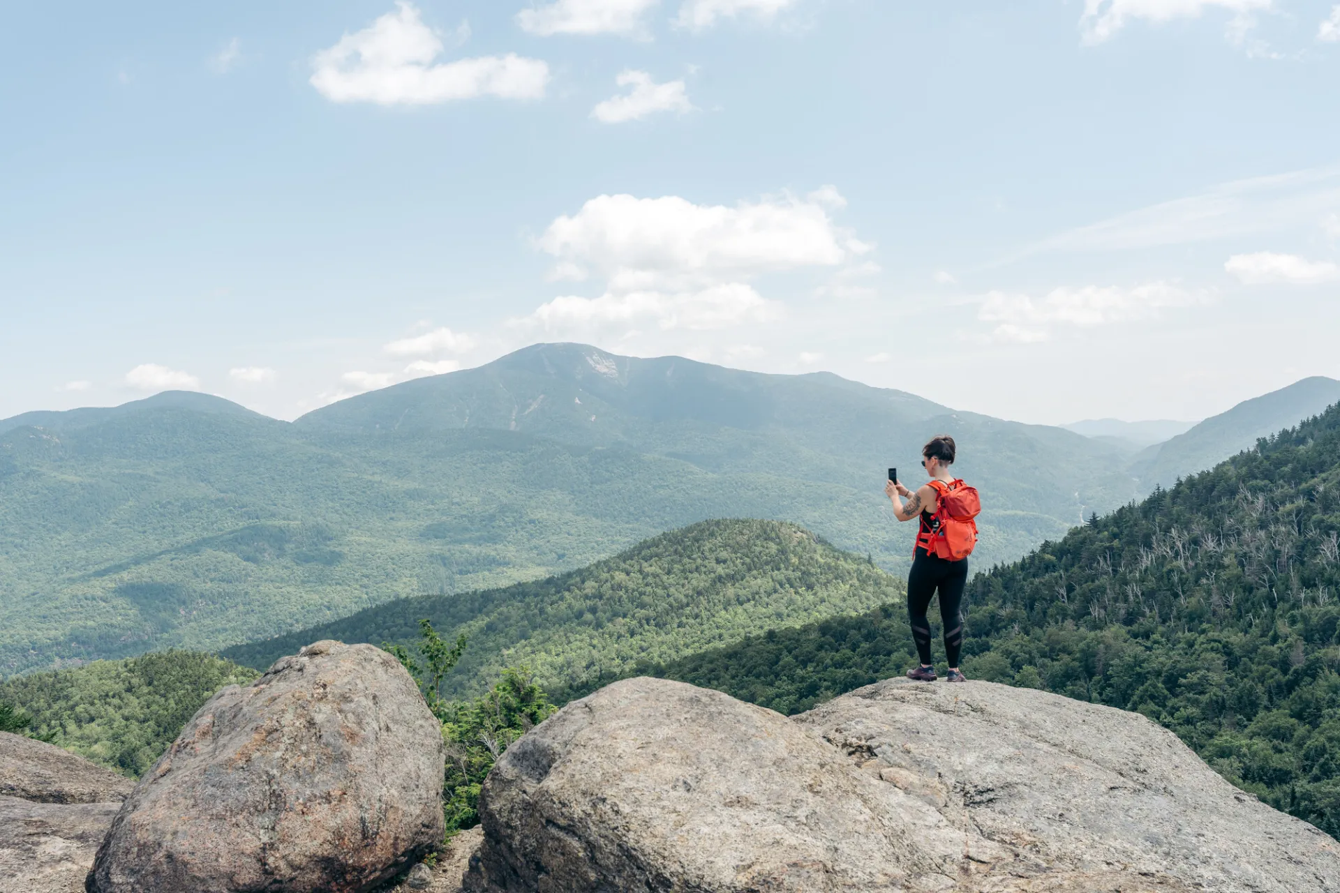 A woman takes a picture on top of a mountain. 