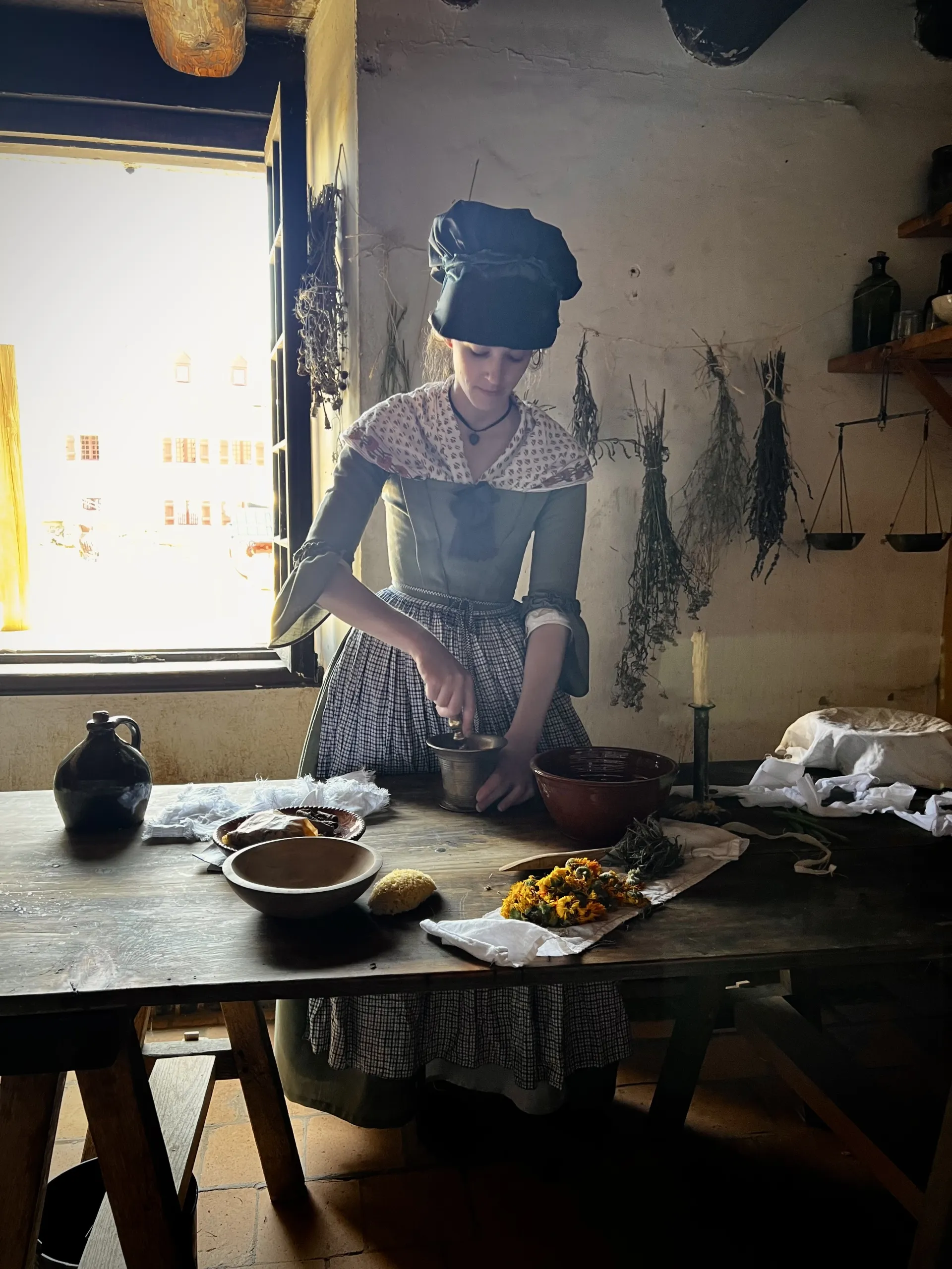 A reenactment performer dressed as a nurse is making traditional medicines from raw ingredients.