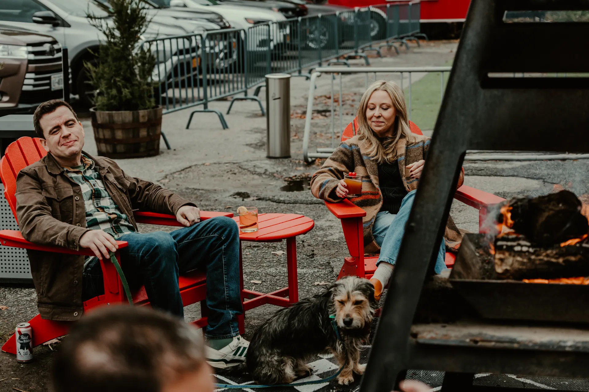 Happy couple enjoys the outdoor space with their pet and some cocktails in red adirondack chairs.  Photo Credit to A. Kelly.