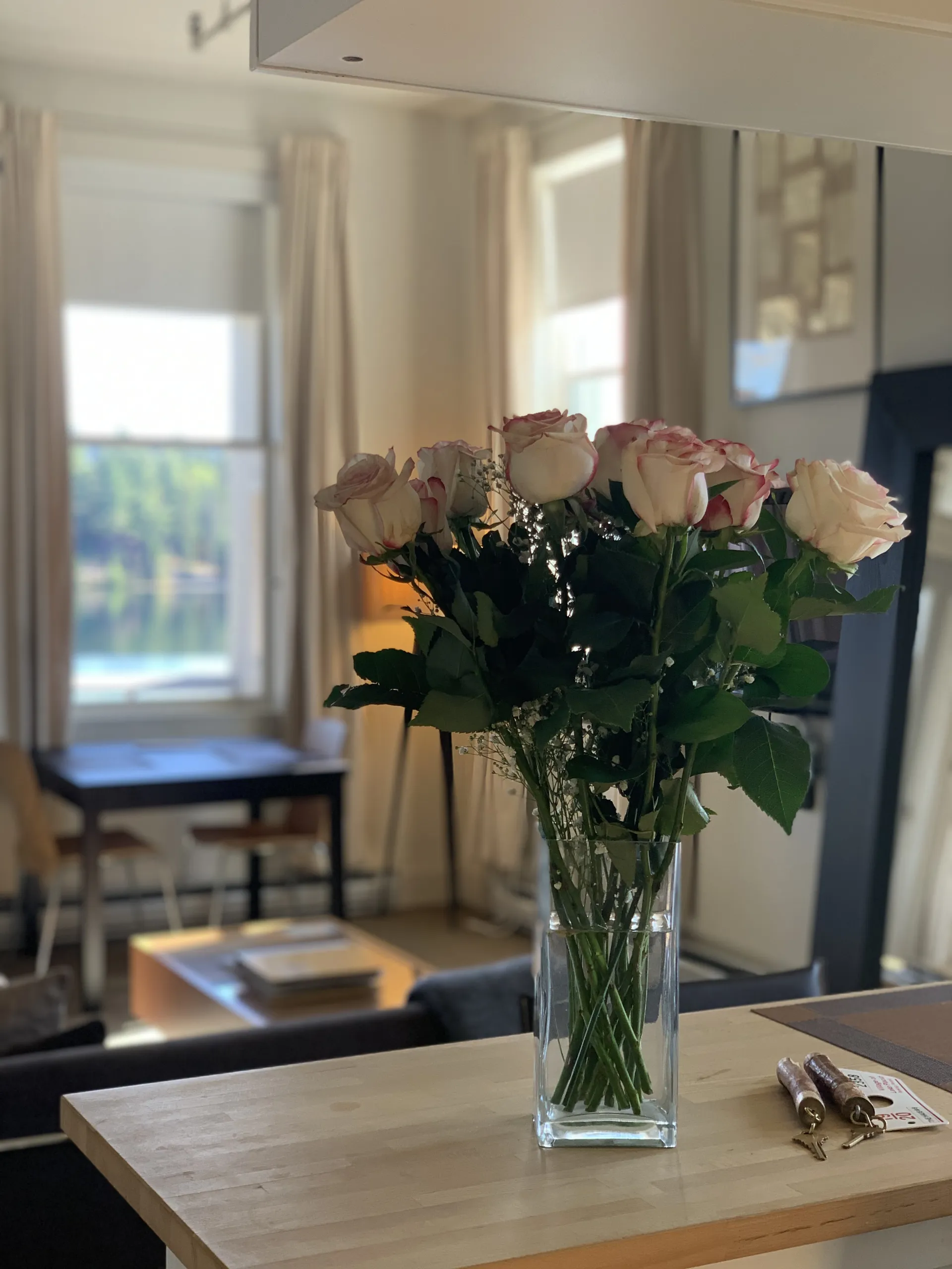 A bouquet of flowers in a vase on a counter by the keys.