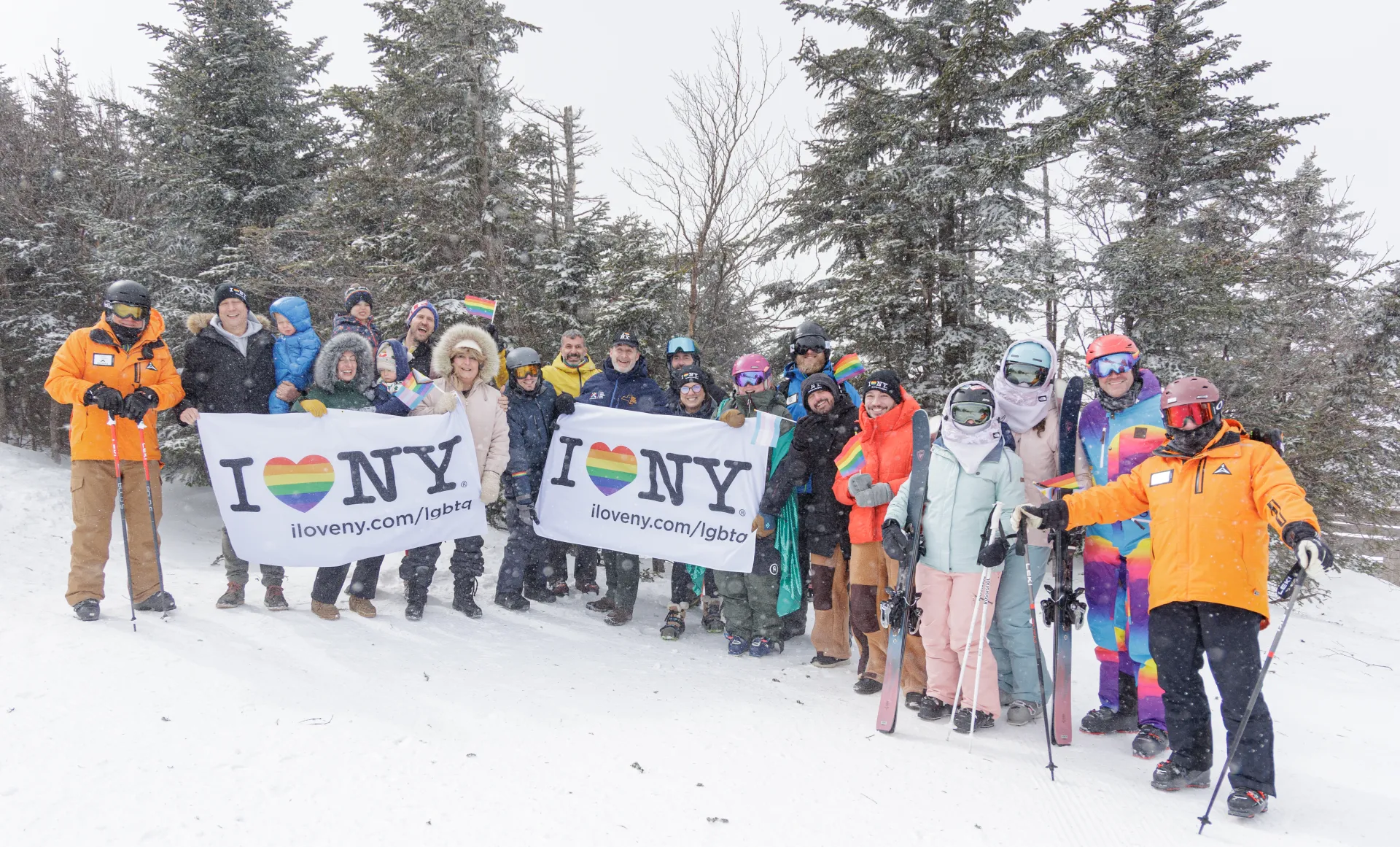 A group of skiers at Whiteface Mountain, holding pride flags and small rainbow flags to celebrate Adirondack Winter Pride.