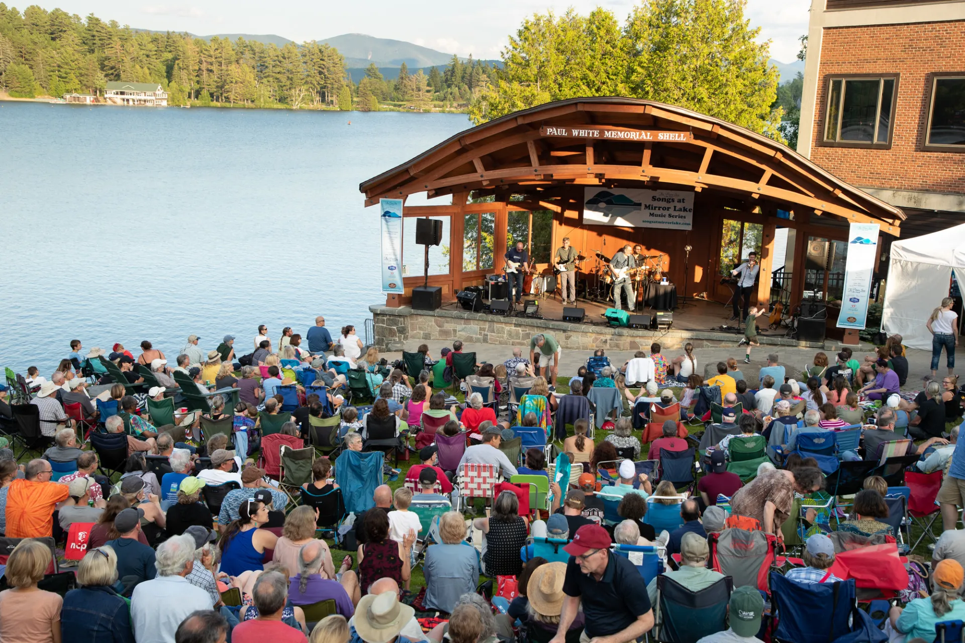 Crowd gathers in Mid's Park on a summer evening to listen to live music.