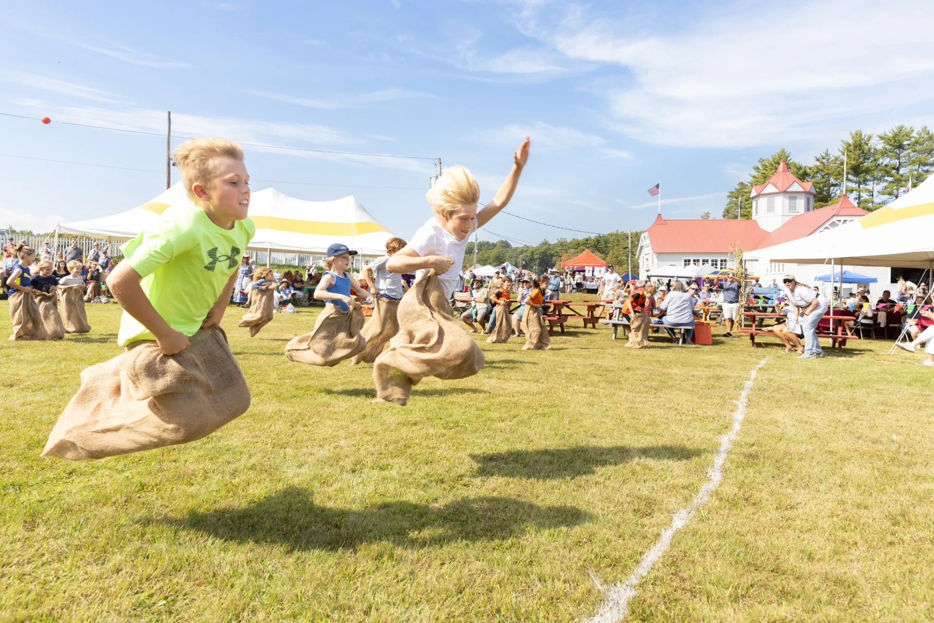 Kids cross finish line in sack races.