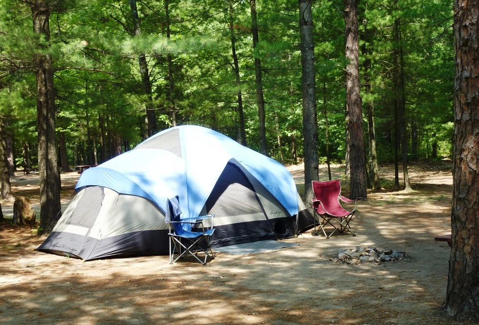 A large tent set up with chairs by the fire pit.