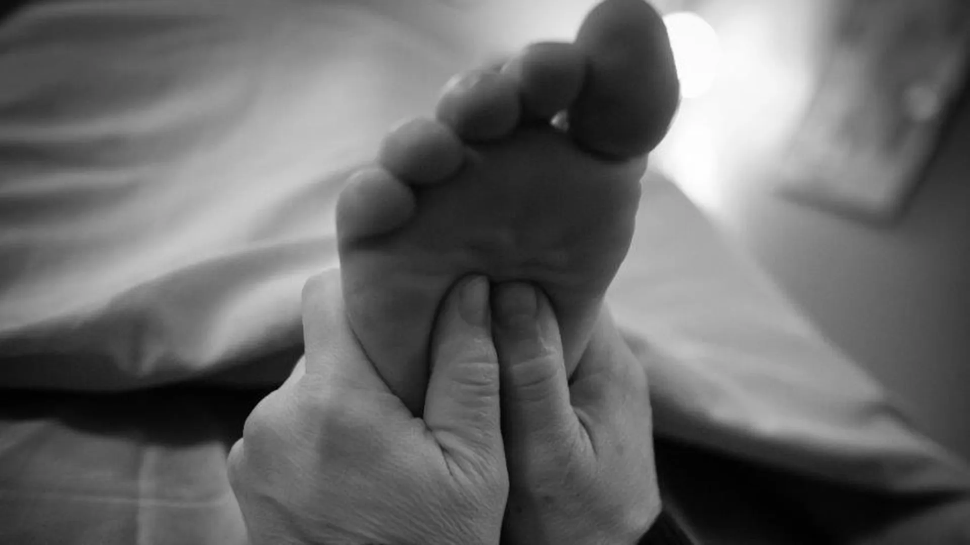 Thumbs apply pressure to the center of a foot during a massage at Healing Elements.
