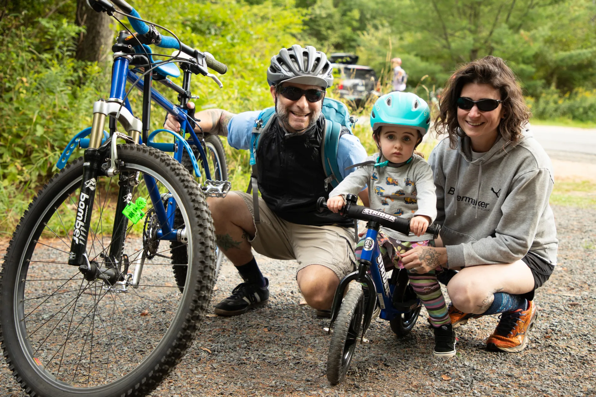 Smiling young family with toddler kick bike