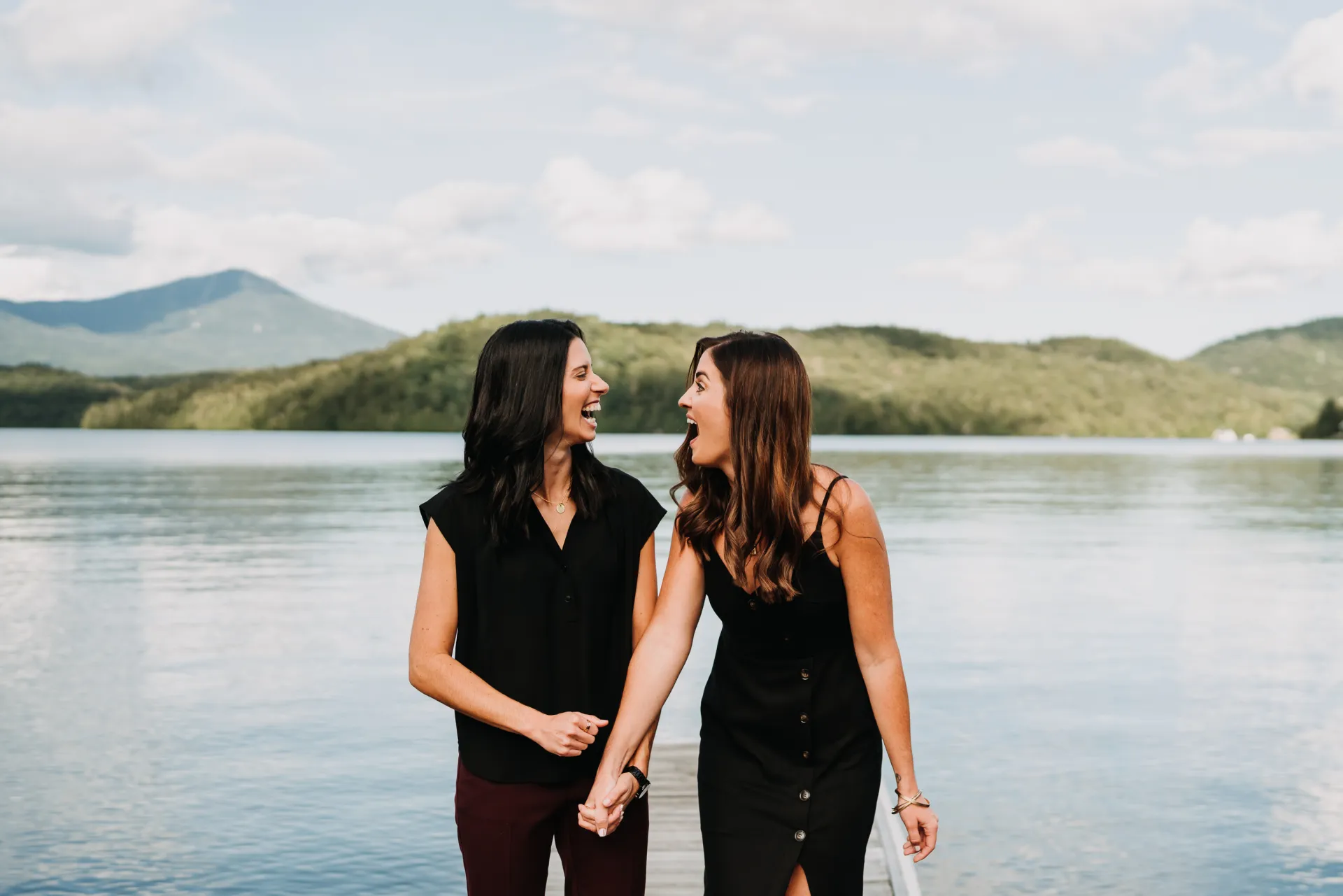 two girls laughing in front of a lake