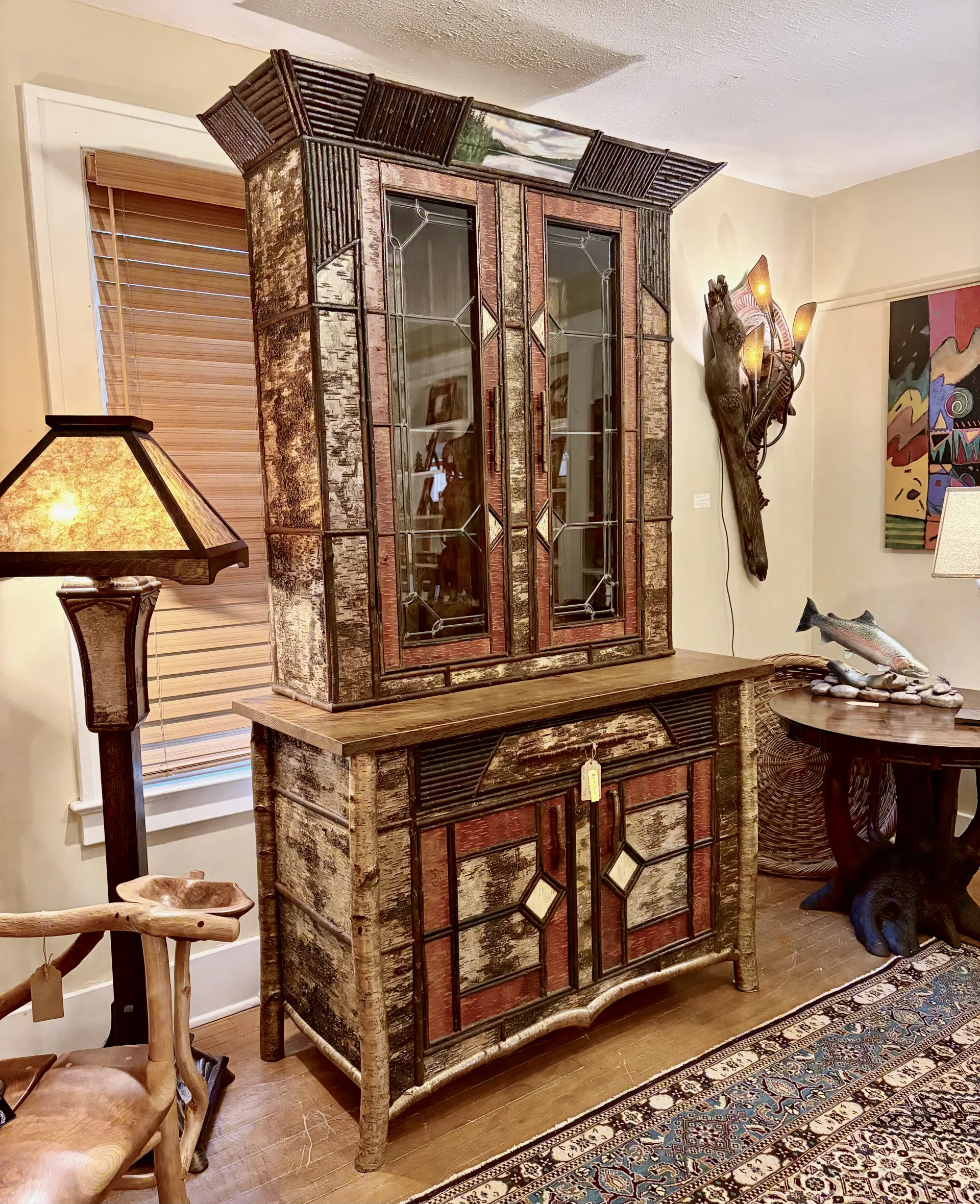 A birch bark decorated hutch with glass windows on the upper doors.