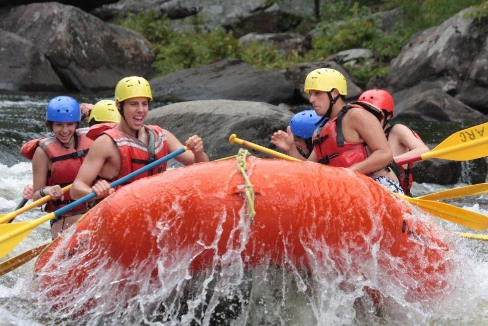 A group of rafters smile and wave at camera