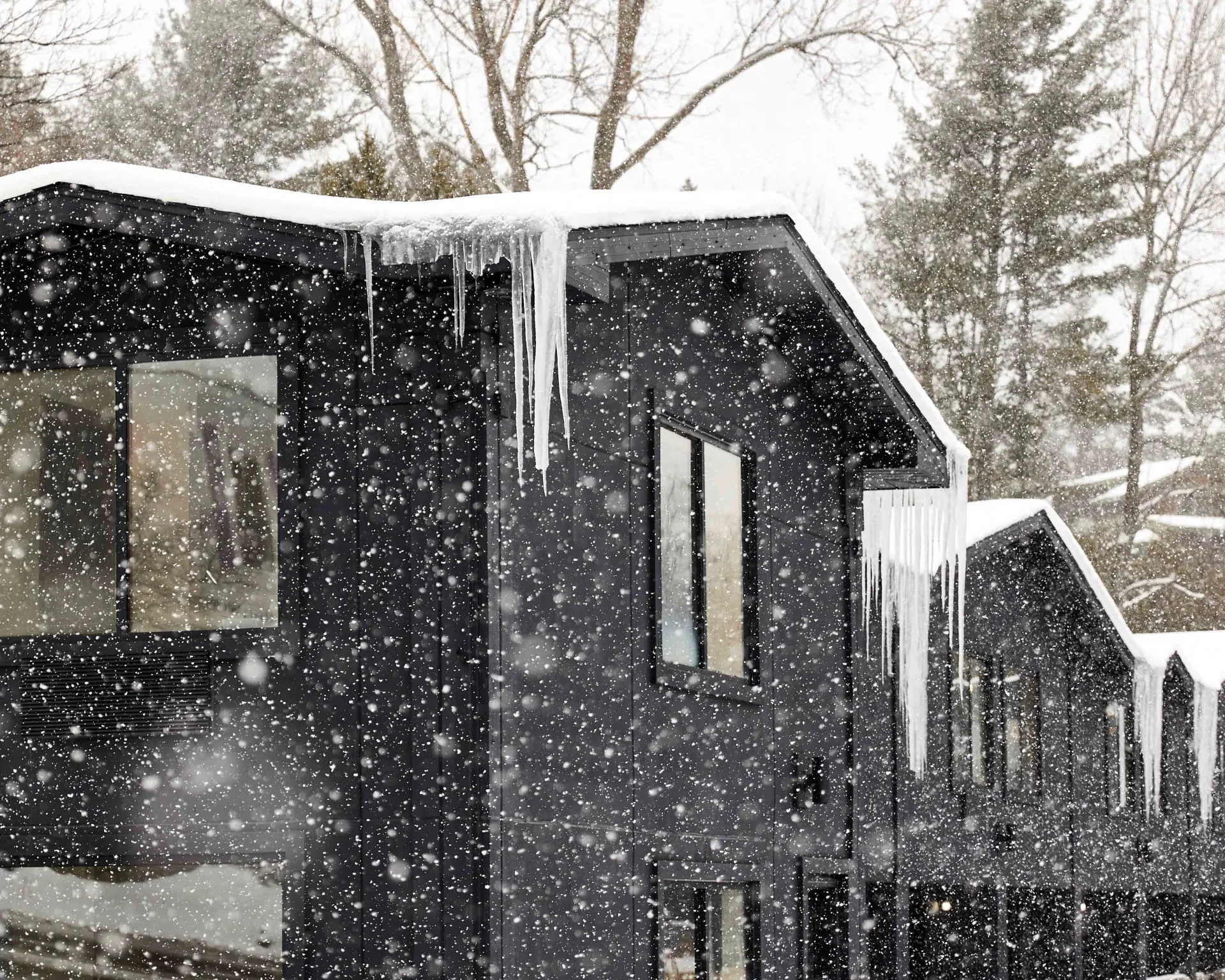 The black exterior of the building contrasting the icicles and freshly falling snow.