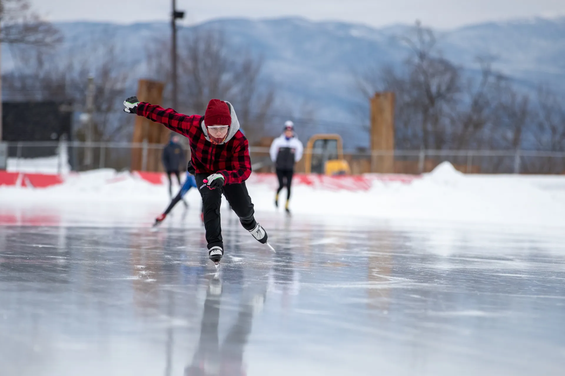 A speed skater in motion with others watching their form.