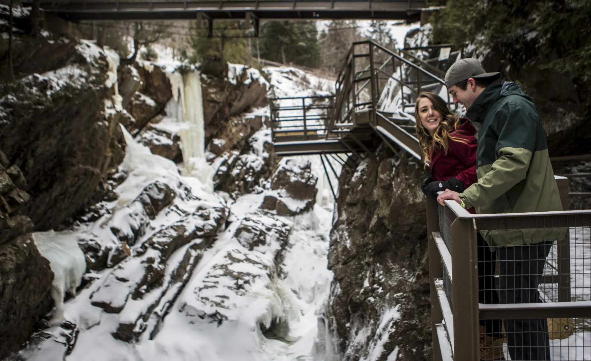 Two people at a frozen waterfall, overlooking from a boardwalk
