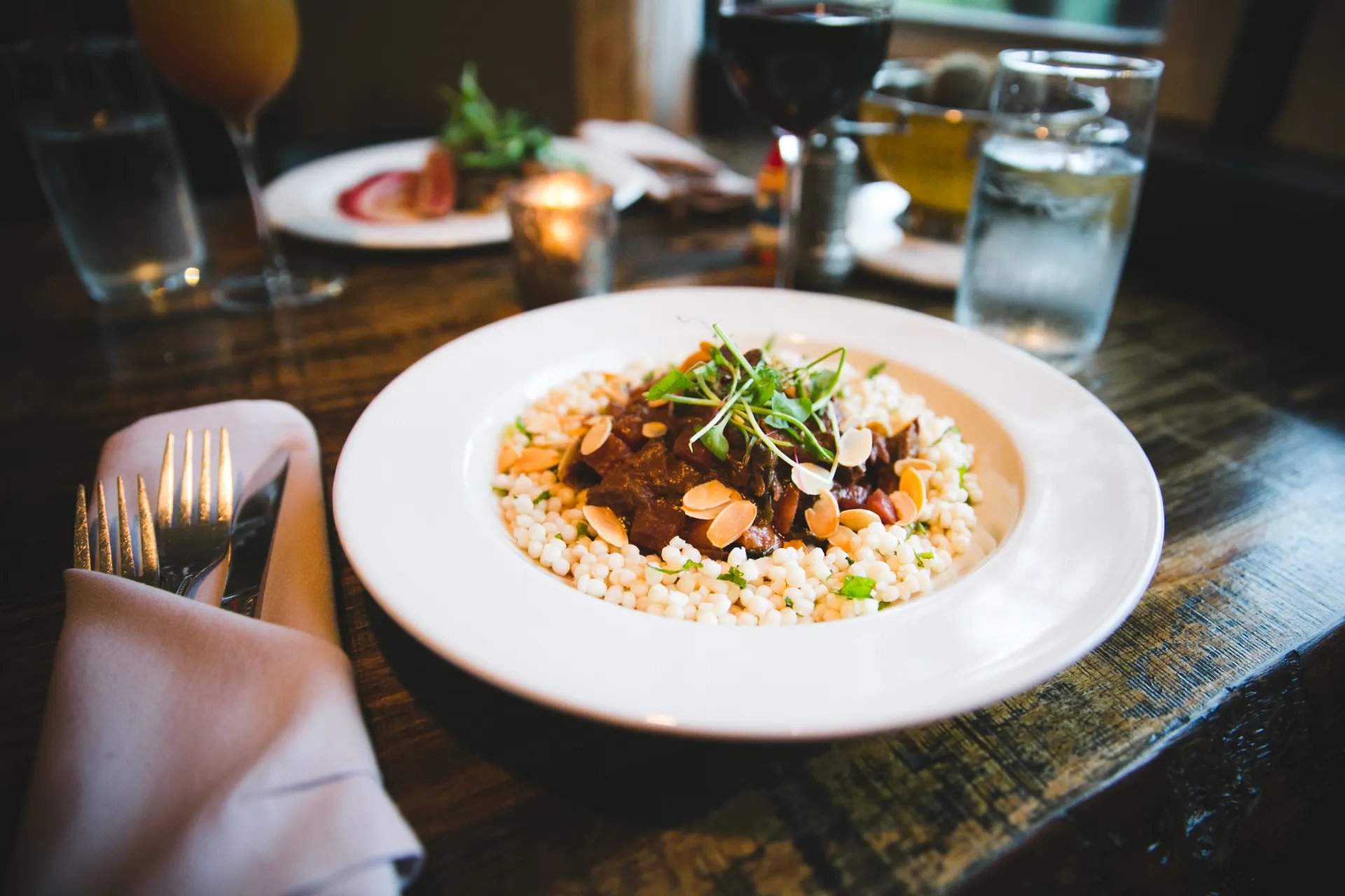A couscous and braised meat on a large white plate.