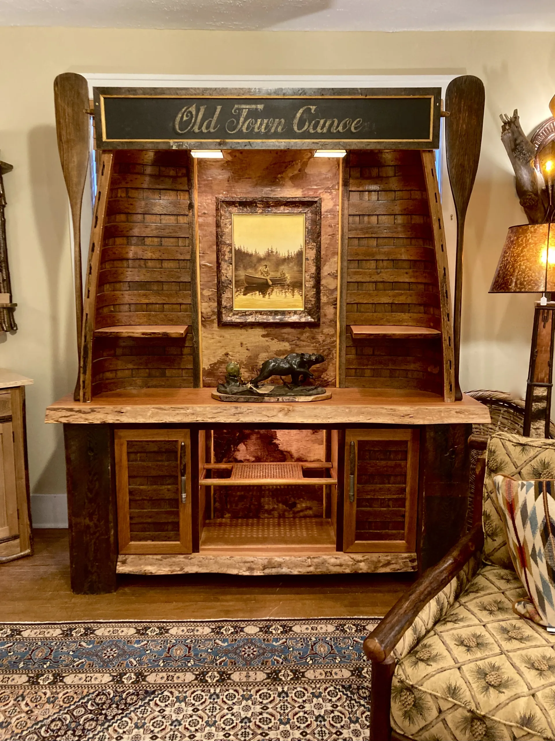 A large hutch created from two wooden ribbed canoes with paddles on the sides.