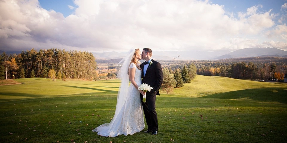 A bride and groom kiss on the green at the Lake Placid Club Golf House.