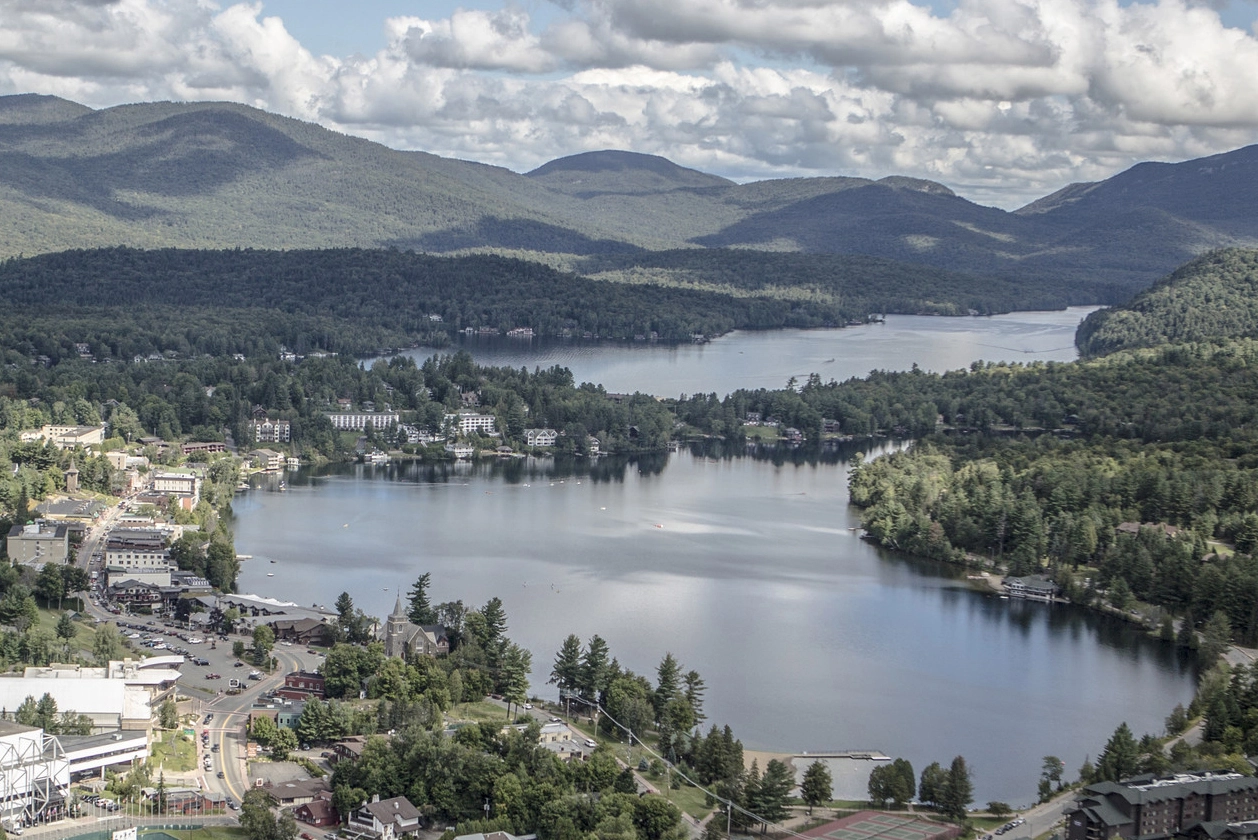 Aerial view of the village of Lake Placid lined with shops and restaurants and adjacent to Lake Placid lake and Mirror Lake.