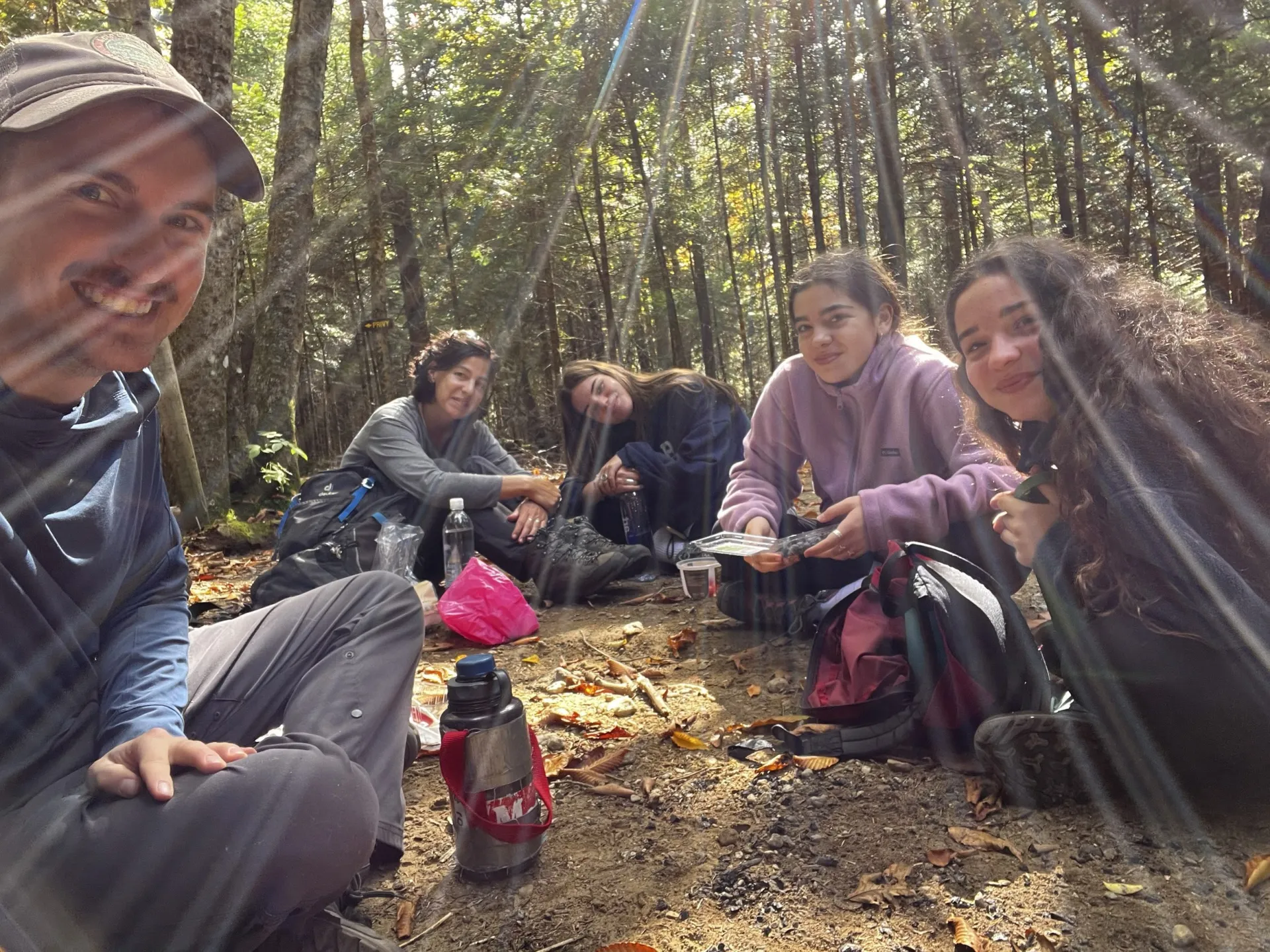 A group sits for a break with sunbeams shining through the trees