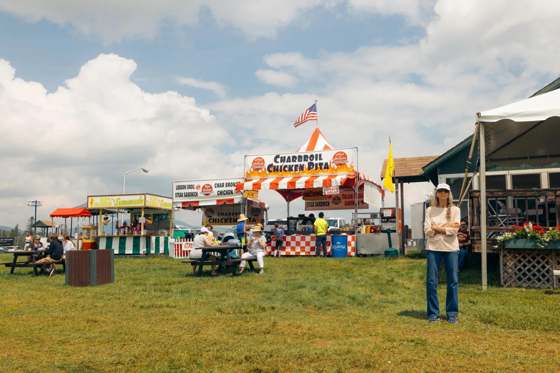 A woman contemplates her options by the vendors while families sit at picnic tables.