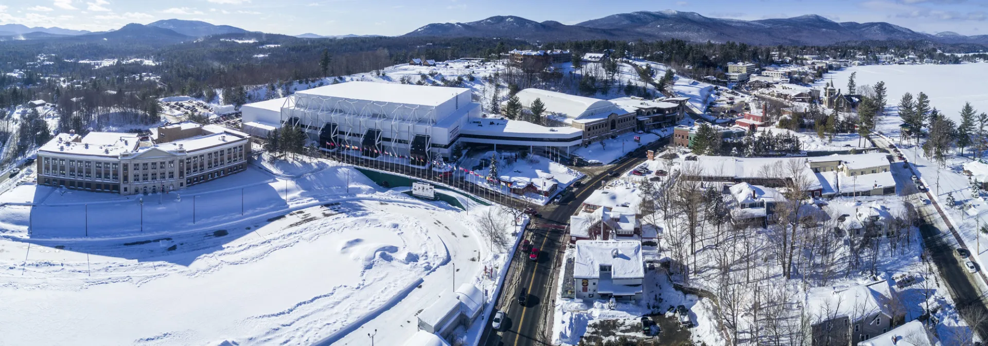 An aerial view of a white building covered in snow sitting at the end of a street. 