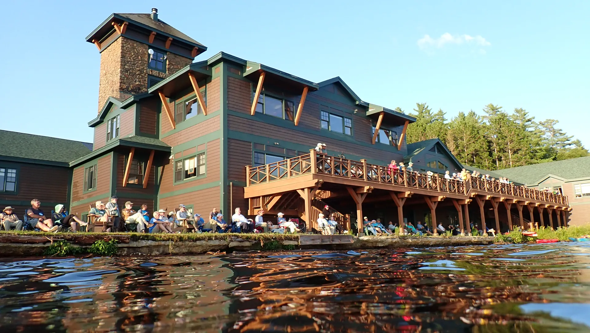 A crowd has gathered on the shore to watch the canoes on the water.