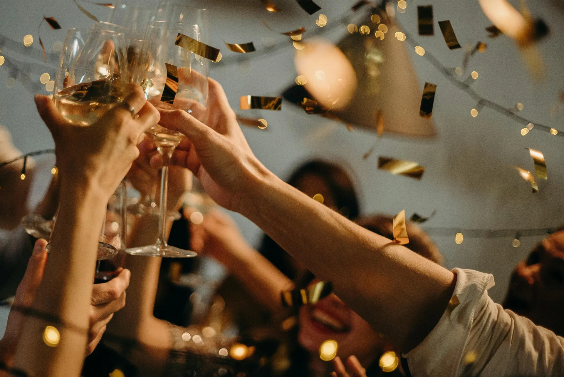 Stock image of hands raising champagne flutes among confetti