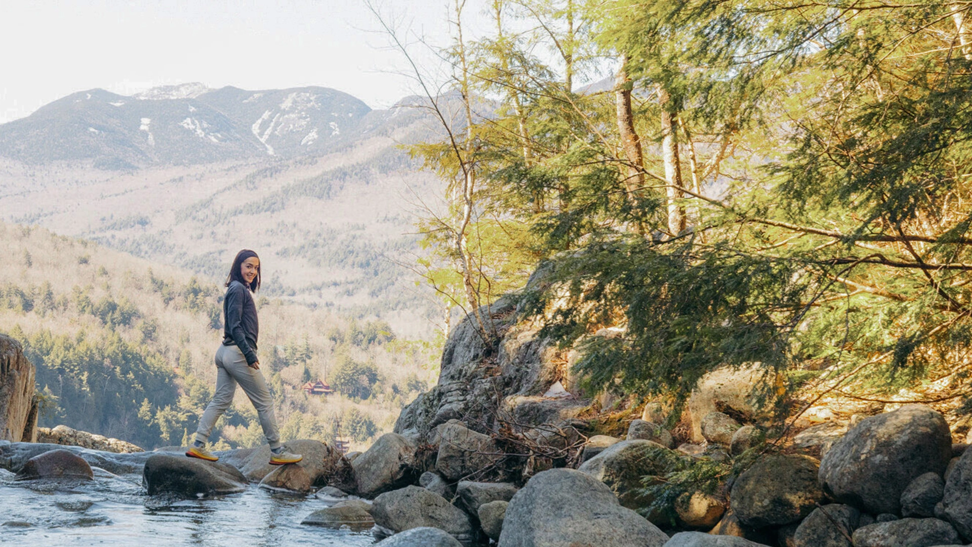 A woman stands at the top of a waterfall. 