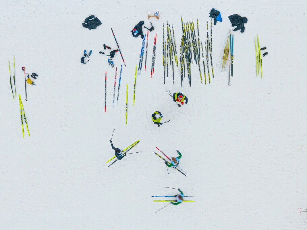 Overhead image of skiers, sets of skis, and other equipment on snow