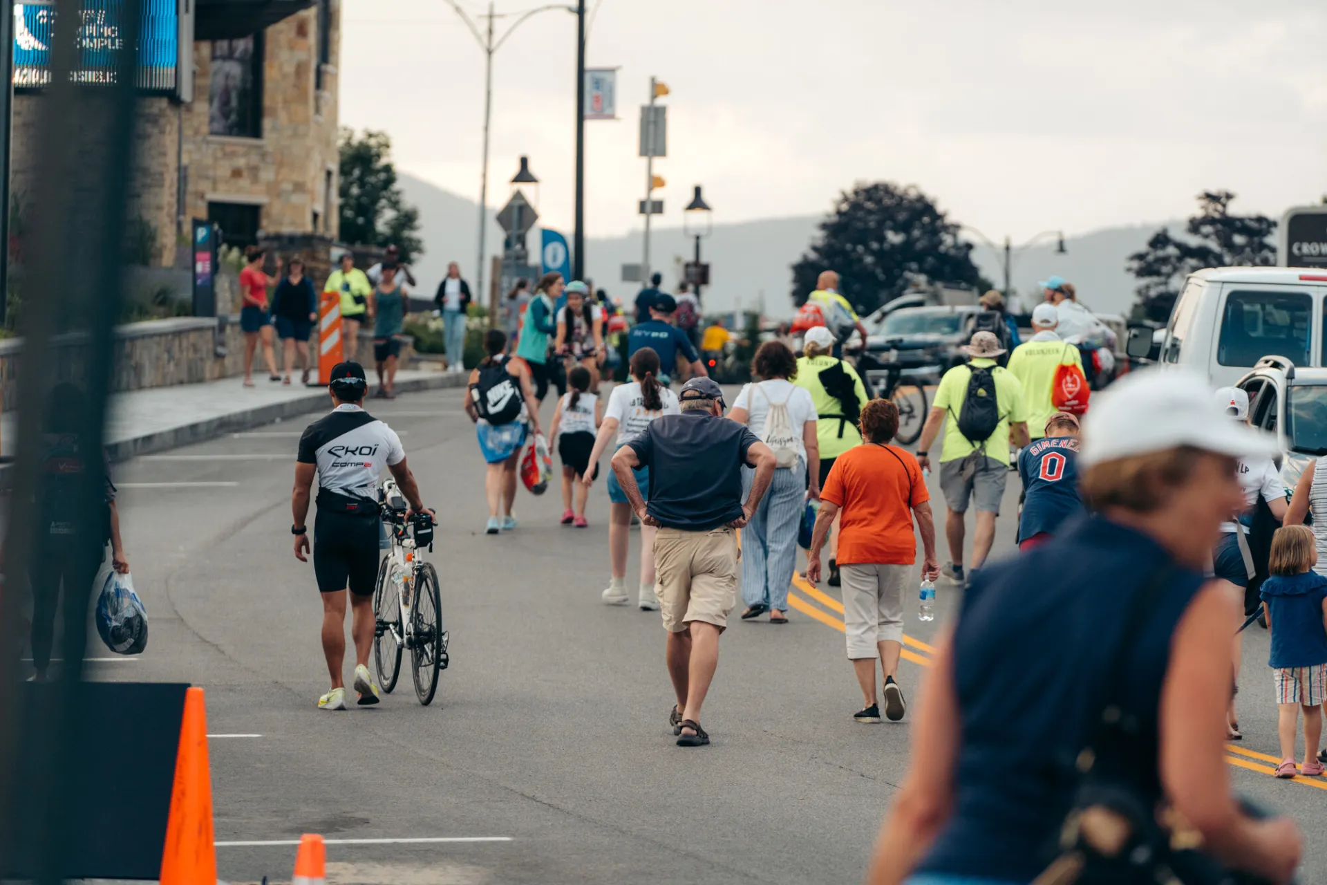 Athletes and spectators walk on road in Lake Placid during Ironman