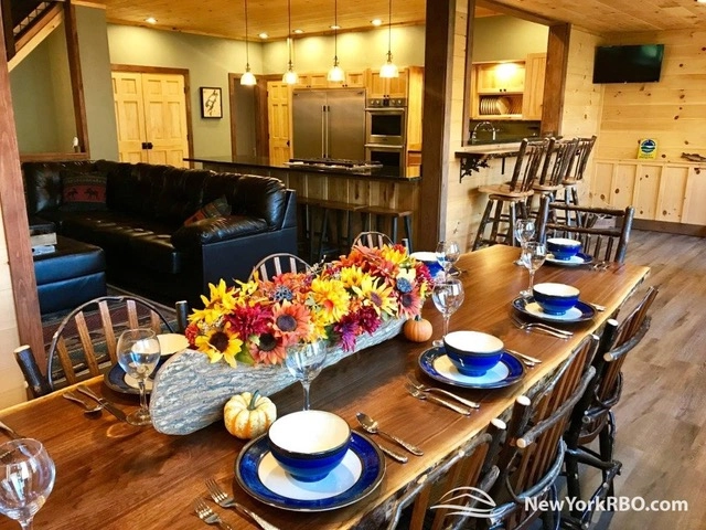 A large dining table set for 8 with sunflower centerpiece and happy blue flatware.