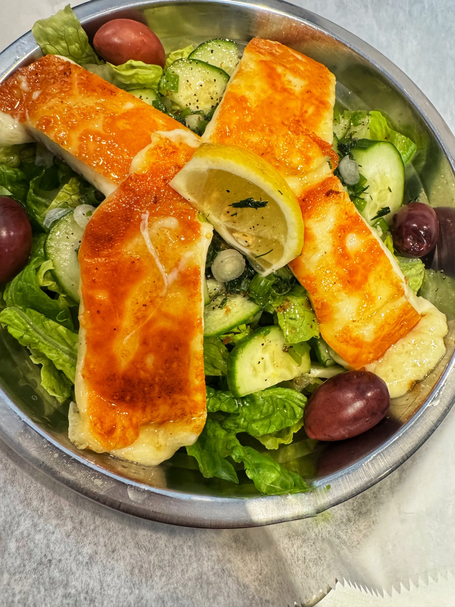 Greek salad topped with Halloumi with lemon