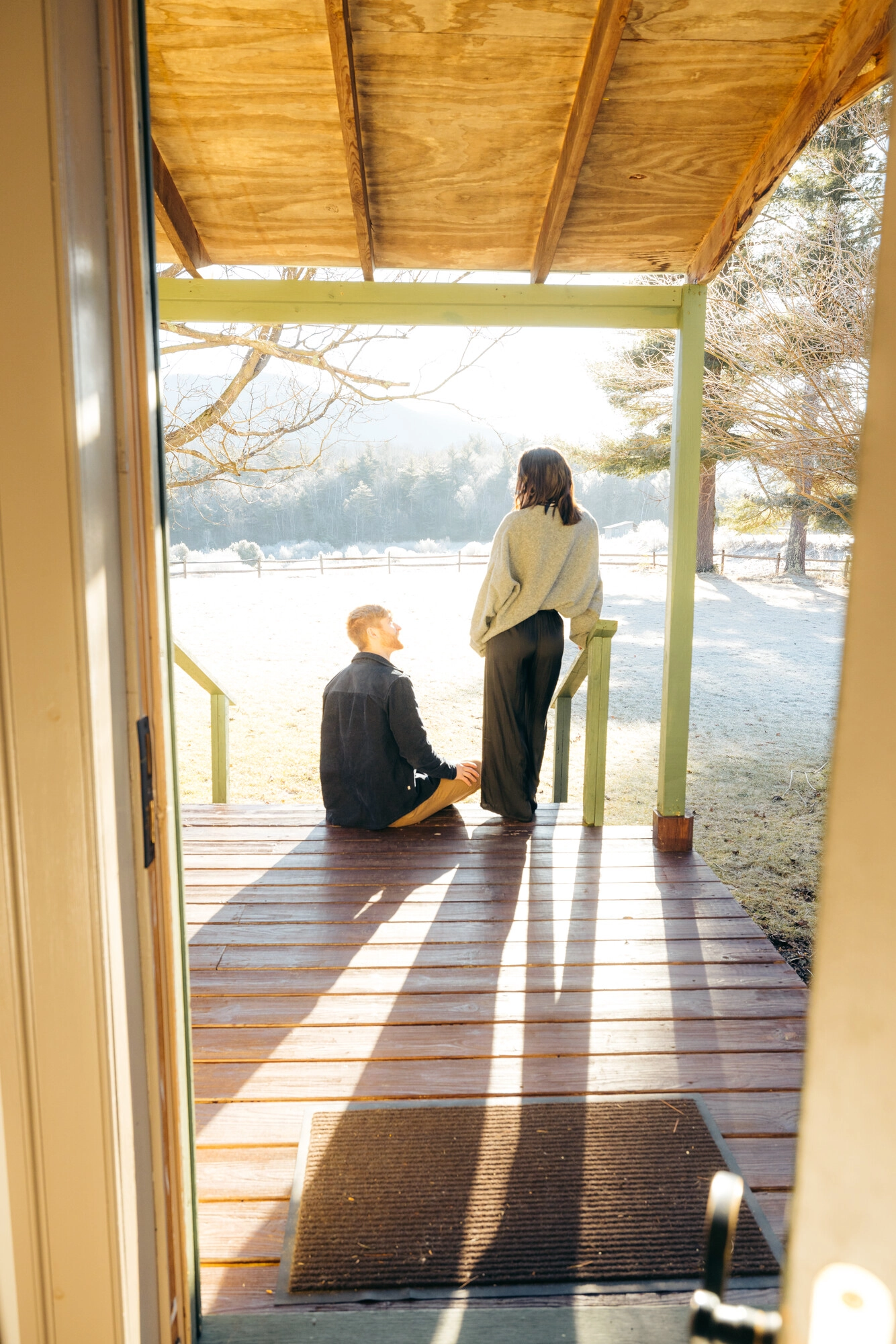 Couple on porch at misty morning, man sitting and woman standing leaning on rail