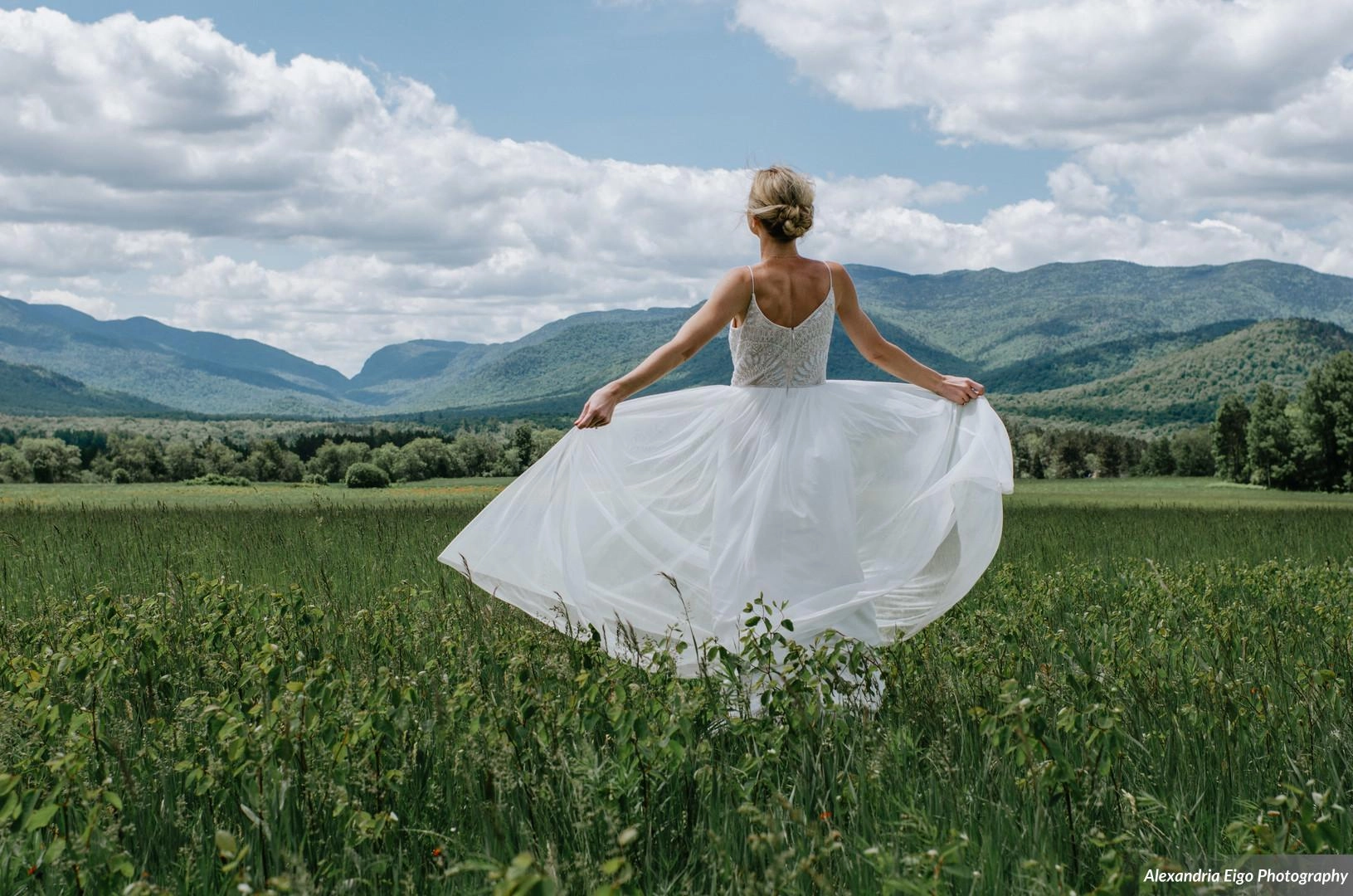A bride fans out her dress and takes in the majestic view of the high peaks