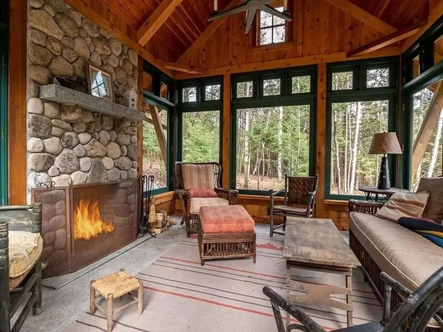 A three season room with tree views and a large stone fireplace.
