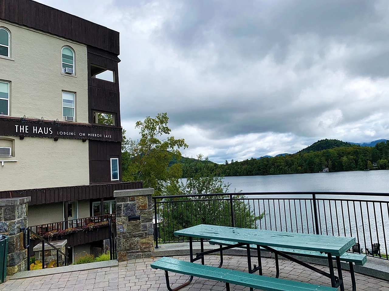 A picnic table on a brick patio next to The Haus viewing Mirror Lake.