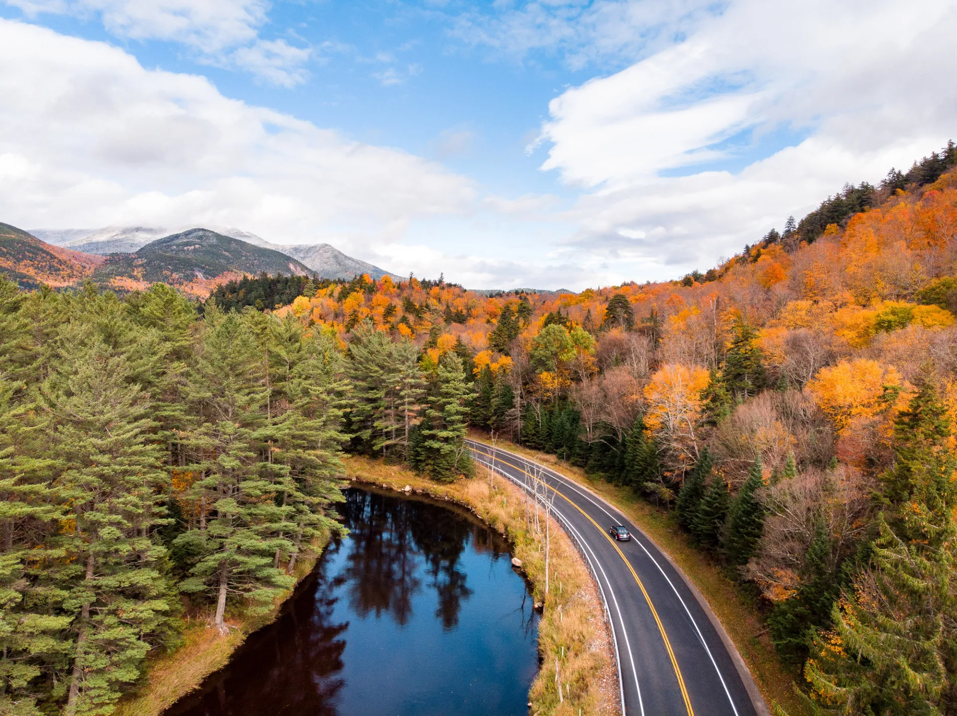 A winding road near a river with fall scenery.