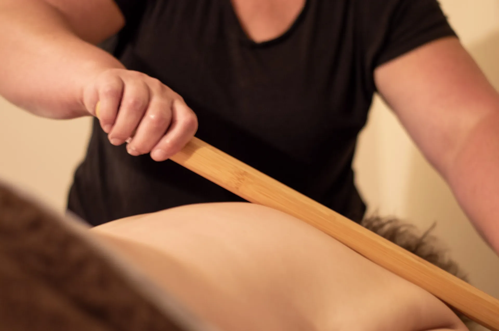 A massage therapist uses a bamboo tool to deepen the treatment at Healing Elements