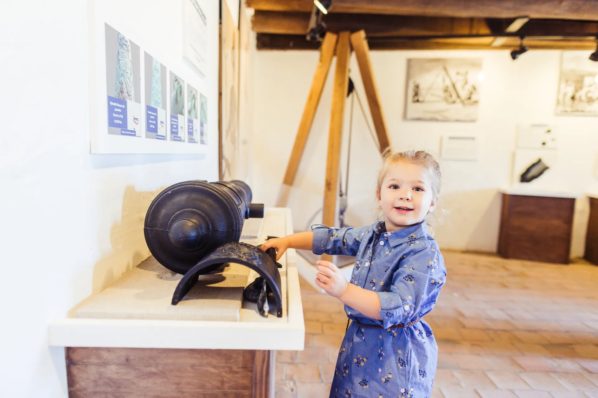 A little girl inspects a display of a cannon