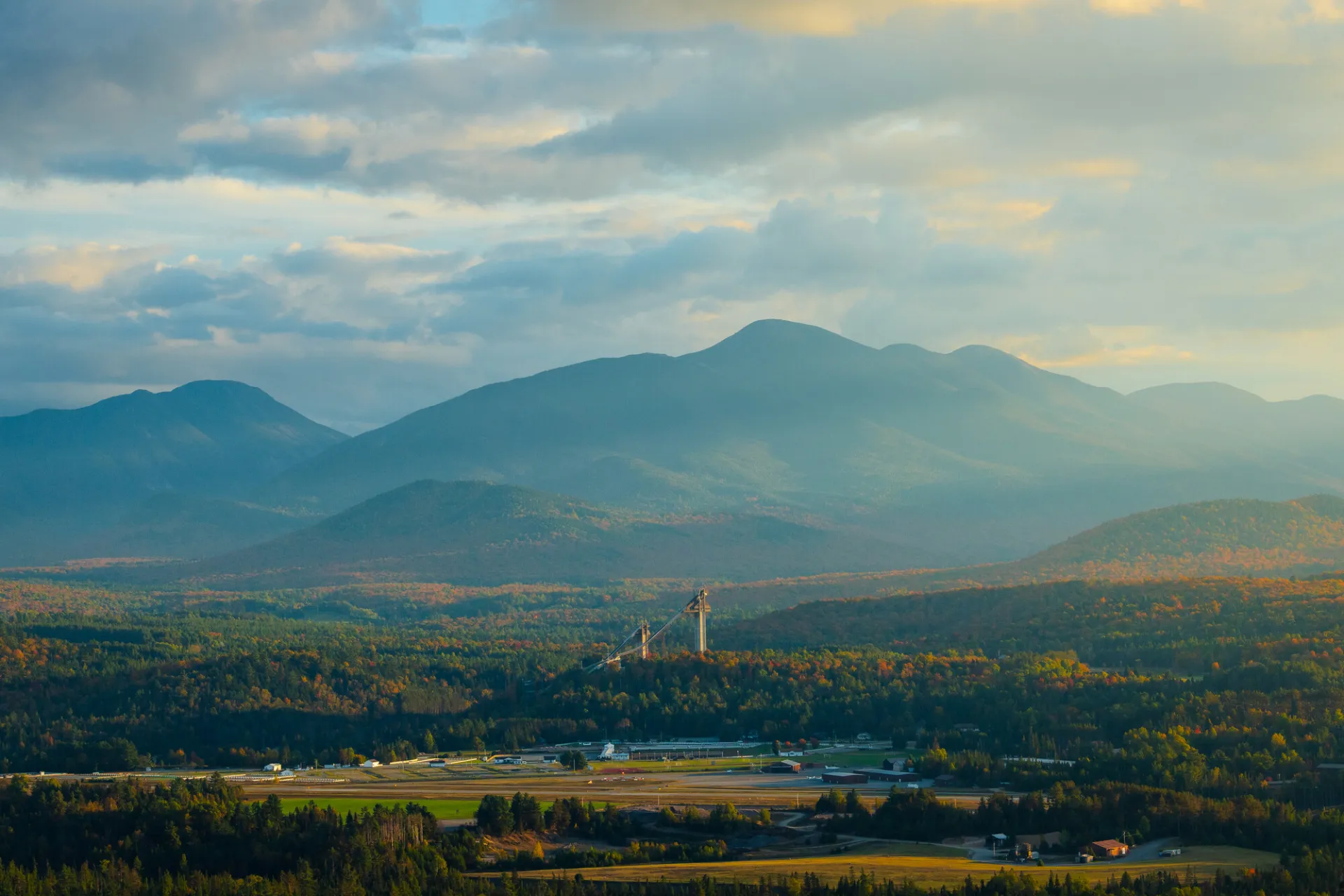 A wide open mountain scape with olympic ski jumps in the center during fall.