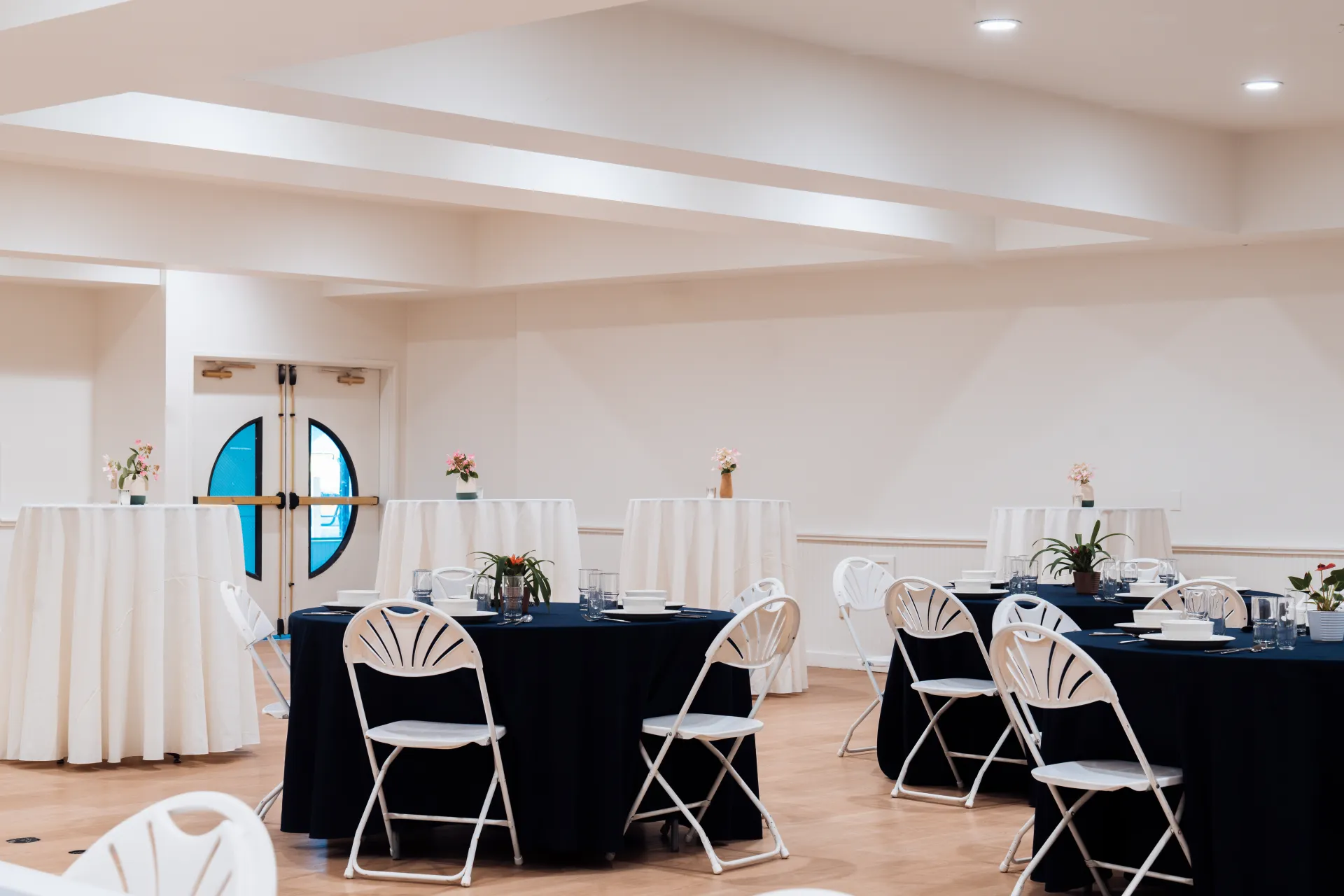 A bright white space with tables at seat height, ringed with bar height tables.