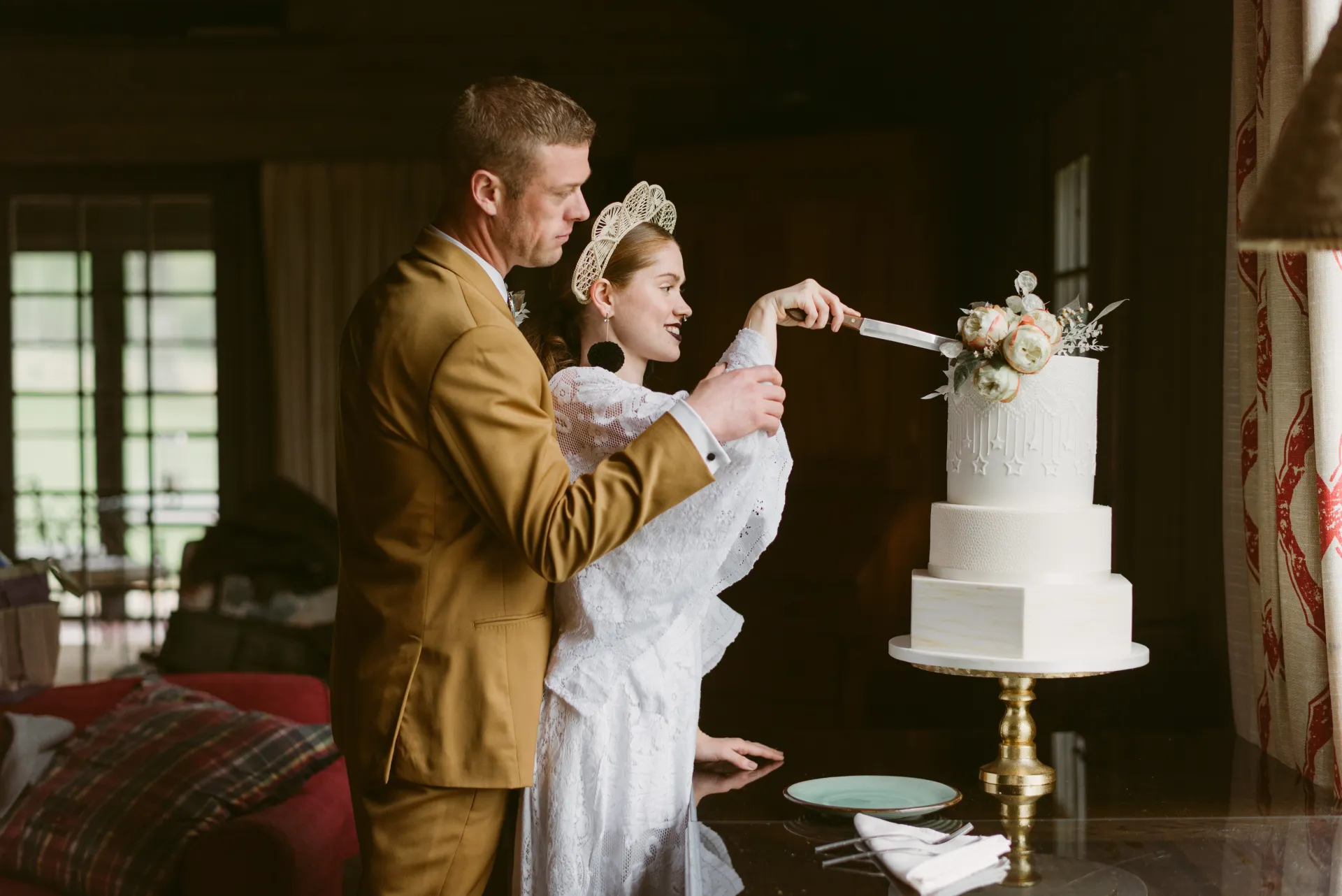 a bride and groom smile as they cut their wedding cake